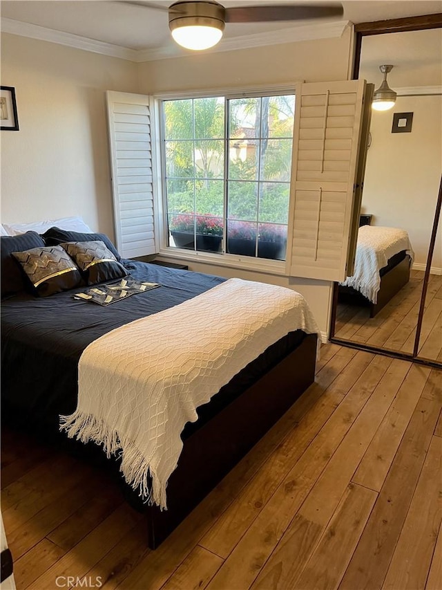 bedroom featuring a closet, ceiling fan, crown molding, and wood-type flooring