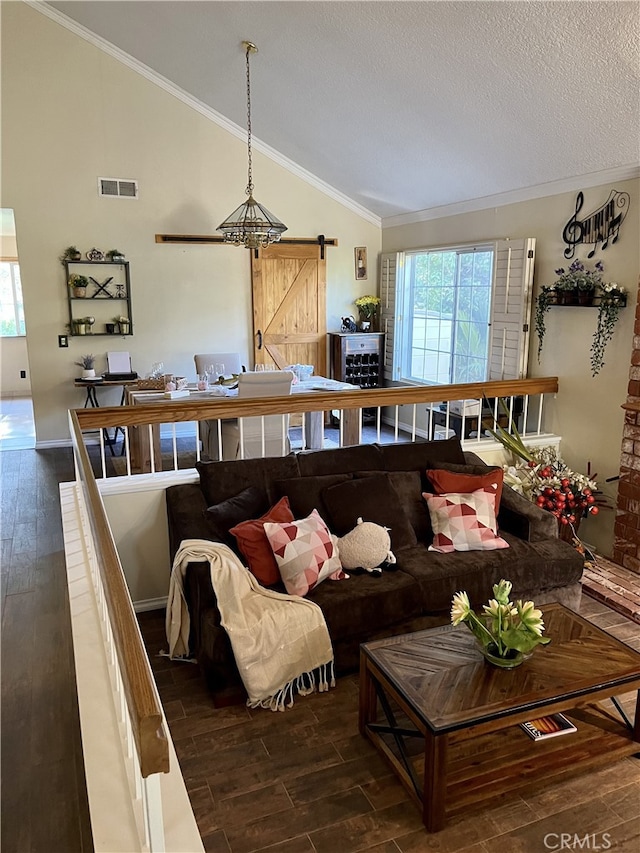 living room featuring crown molding, dark hardwood / wood-style flooring, lofted ceiling, and a barn door