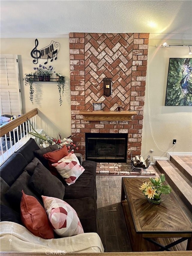 living room with a fireplace, hardwood / wood-style floors, a textured ceiling, and crown molding