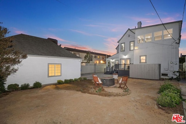 back house at dusk with an outdoor fire pit