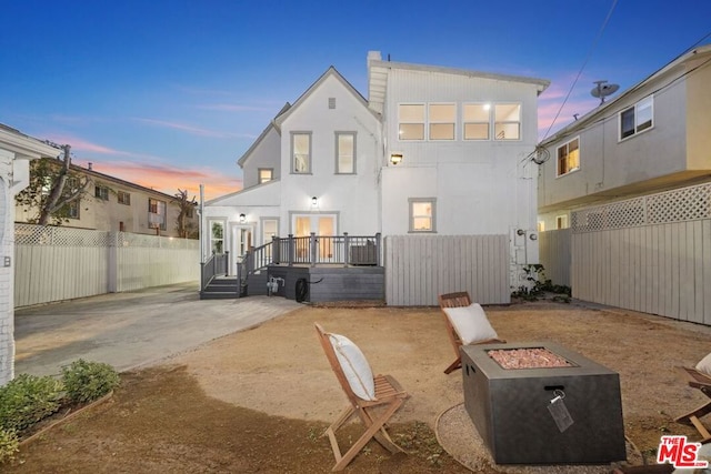 back house at dusk with a fire pit and a patio