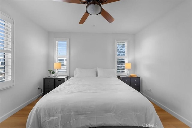 bedroom with multiple windows, light hardwood / wood-style flooring, and ceiling fan