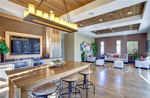 kitchen featuring wood ceiling, a breakfast bar, a raised ceiling, and hardwood / wood-style floors