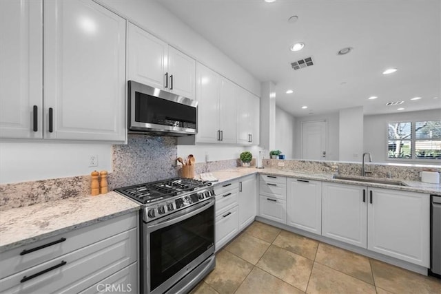 kitchen featuring appliances with stainless steel finishes, light stone countertops, sink, and white cabinets