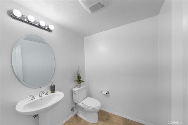 bathroom featuring tile patterned floors, toilet, sink, and a textured ceiling