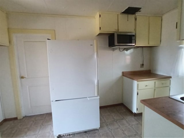 kitchen featuring cream cabinetry and white fridge