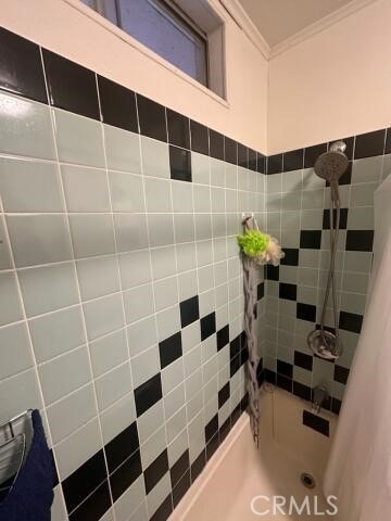 bathroom with tiled shower / bath combo and ornamental molding