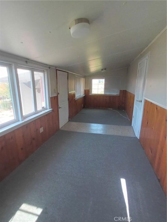 spare room with wood walls and lofted ceiling