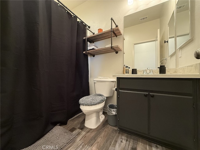 bathroom featuring wood-type flooring, toilet, and vanity