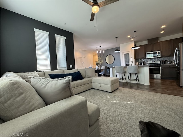 living room featuring ceiling fan with notable chandelier and carpet