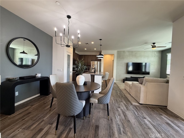 dining area with ceiling fan with notable chandelier and dark hardwood / wood-style floors