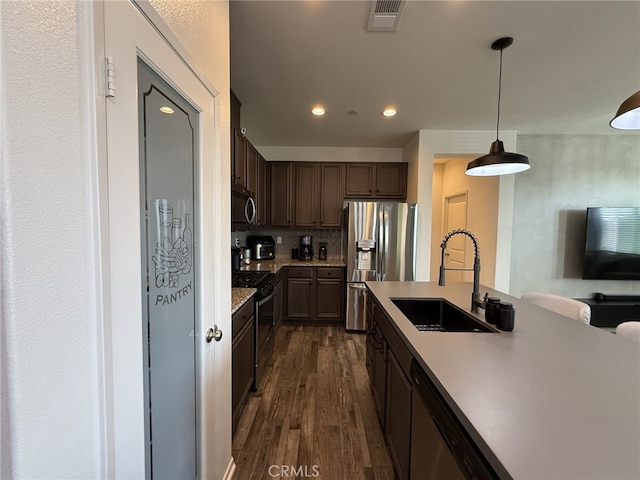 kitchen featuring hanging light fixtures, sink, backsplash, dark wood-type flooring, and stainless steel appliances