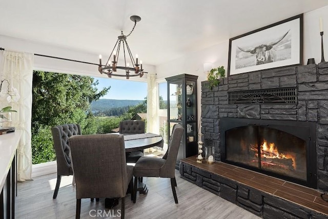 dining space featuring a notable chandelier, a fireplace, and wood-type flooring