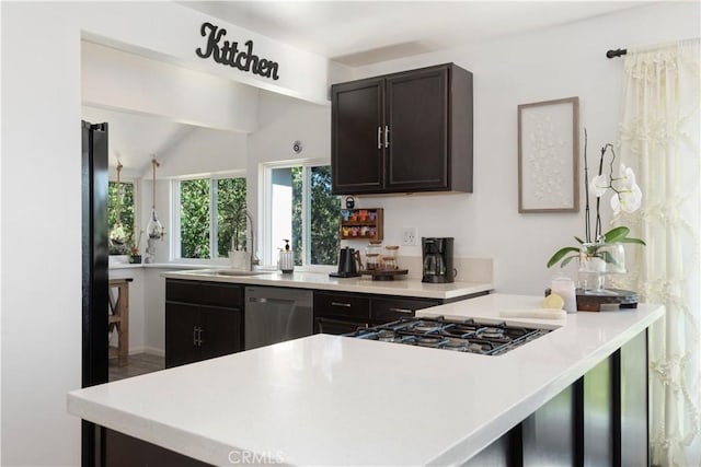 kitchen with kitchen peninsula, dark brown cabinets, vaulted ceiling, sink, and black appliances