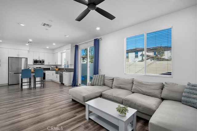 living room featuring hardwood / wood-style flooring, sink, and ceiling fan