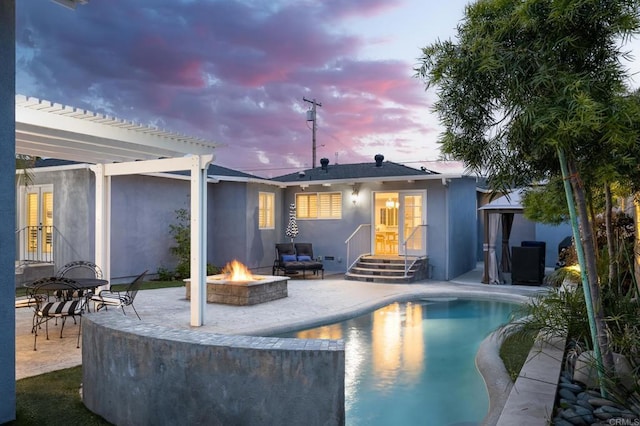 back house at dusk with an outdoor fire pit, a pergola, and a patio area