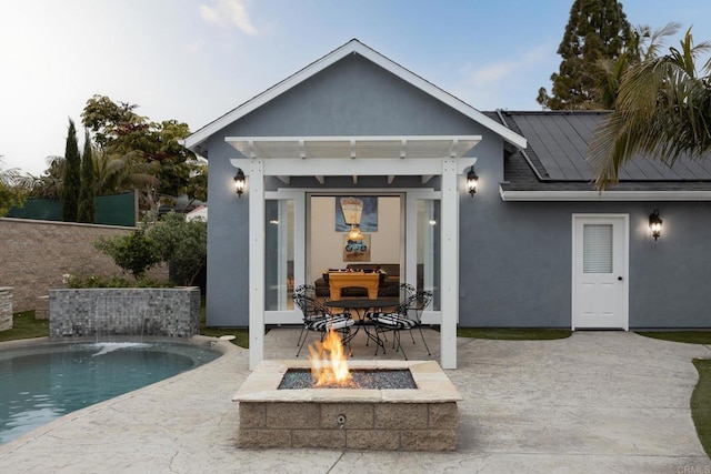 rear view of house featuring an outbuilding, a fire pit, pool water feature, and a patio