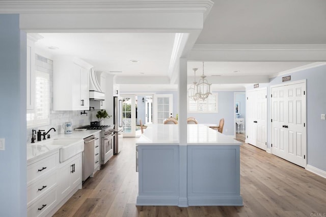 kitchen featuring sink, light wood-type flooring, white cabinetry, a kitchen island, and stainless steel appliances