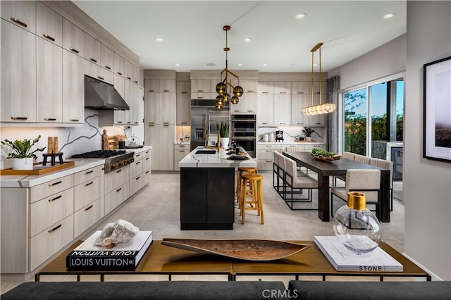 kitchen with pendant lighting, sink, a breakfast bar, a center island with sink, and stainless steel appliances