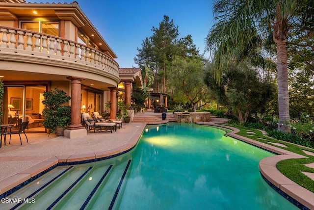 pool at dusk featuring an outdoor living space, an in ground hot tub, and a patio area