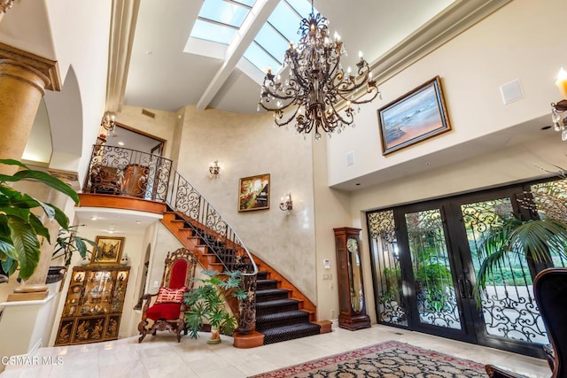 foyer with a notable chandelier, a skylight, french doors, high vaulted ceiling, and beam ceiling