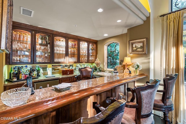 bar featuring sink, a wealth of natural light, and light stone counters