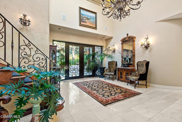 tiled foyer with french doors, a chandelier, and a towering ceiling