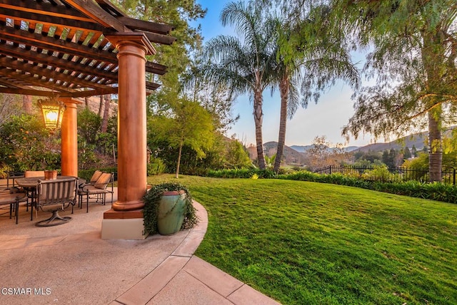 yard at dusk with a mountain view, a patio, and a pergola