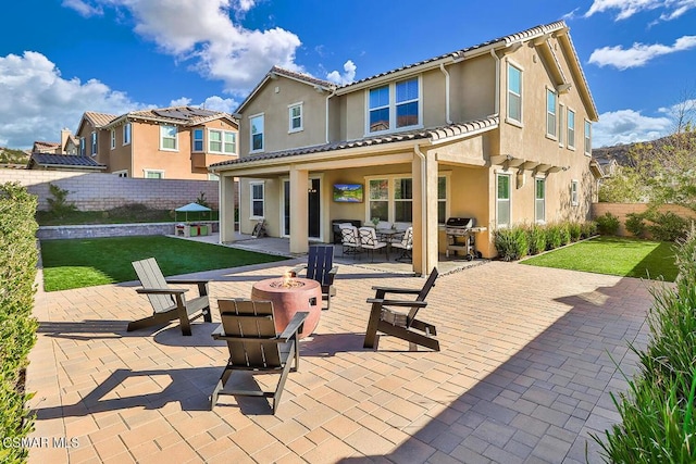 rear view of house featuring a patio, a lawn, and an outdoor fire pit