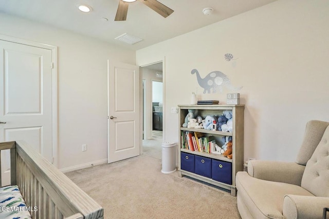 carpeted bedroom with a nursery area and ceiling fan