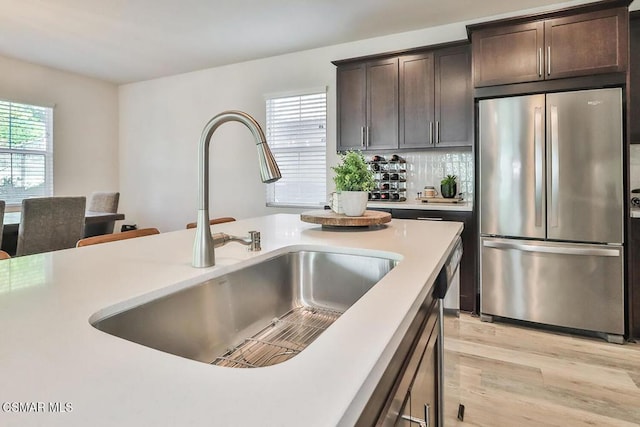 kitchen featuring stainless steel refrigerator, a healthy amount of sunlight, dark brown cabinetry, and sink