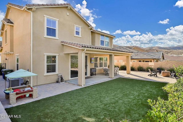 rear view of property featuring a lawn and a patio area