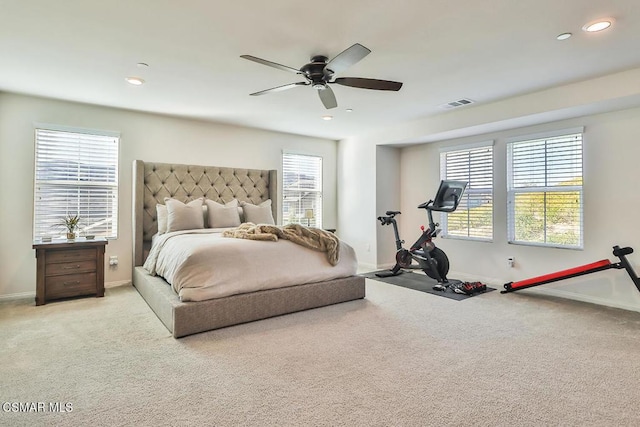 bedroom featuring multiple windows, light colored carpet, and ceiling fan