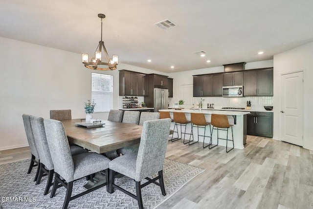 dining space with a notable chandelier and light wood-type flooring