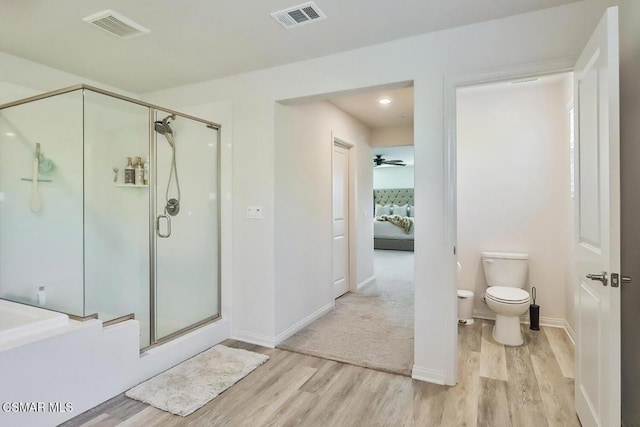 bathroom featuring hardwood / wood-style flooring, plus walk in shower, and toilet