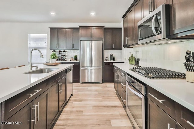 kitchen featuring dark brown cabinetry, sink, light wood-type flooring, and appliances with stainless steel finishes