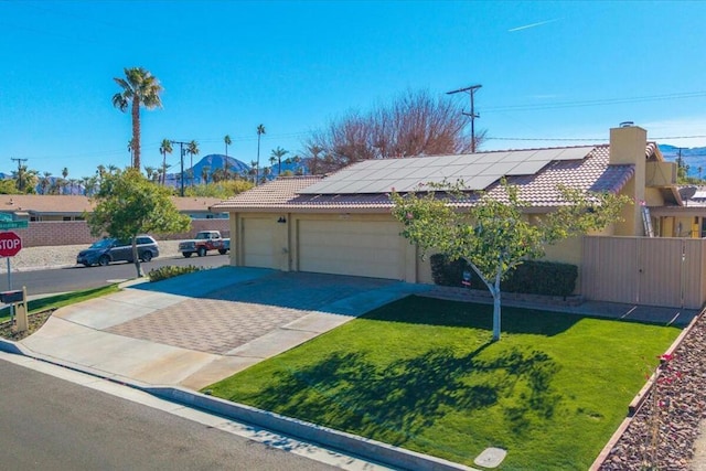 view of front of home with a garage, solar panels, and a front yard