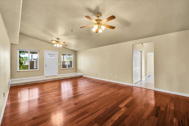 unfurnished living room featuring ceiling fan, wood-type flooring, a textured ceiling, and vaulted ceiling