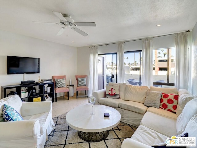 living room featuring light wood-type flooring, ceiling fan, a healthy amount of sunlight, and a textured ceiling