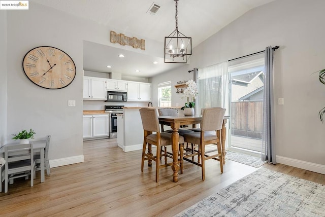 dining space featuring light wood-type flooring, vaulted ceiling, and an inviting chandelier