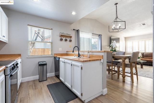 kitchen with white cabinetry, hanging light fixtures, stove, sink, and butcher block countertops