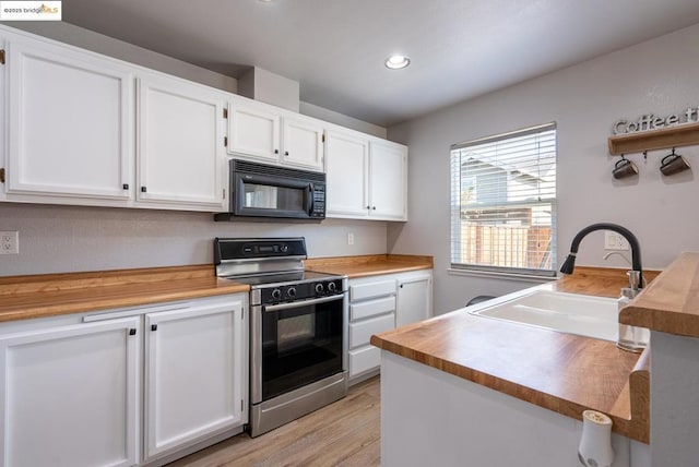 kitchen with white cabinets, stainless steel range oven, butcher block counters, light hardwood / wood-style floors, and sink