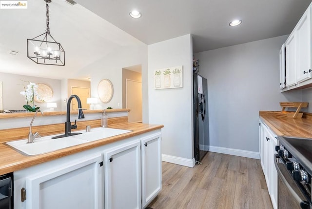 kitchen featuring white cabinetry, sink, pendant lighting, and black appliances