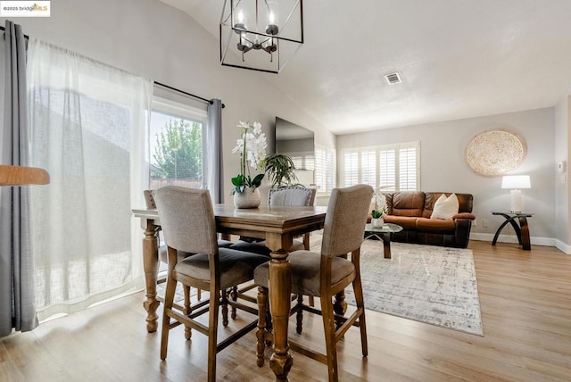 dining room featuring light hardwood / wood-style floors, a notable chandelier, and lofted ceiling