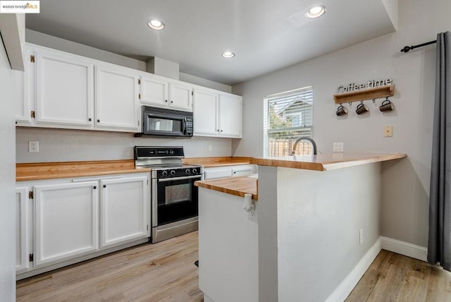 kitchen featuring white cabinets, wood counters, kitchen peninsula, and stove