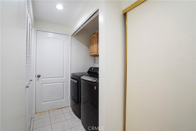 laundry room with light tile patterned floors, cabinets, and washing machine and clothes dryer