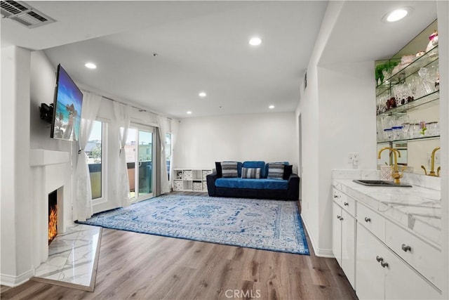 living room with wet bar, light hardwood / wood-style floors, and a tile fireplace