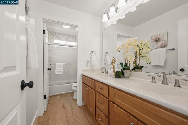 full bathroom with wood-type flooring, toilet, vanity, and bath / shower combo with glass door