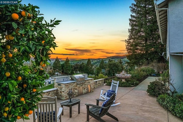 patio terrace at dusk featuring a grill and area for grilling