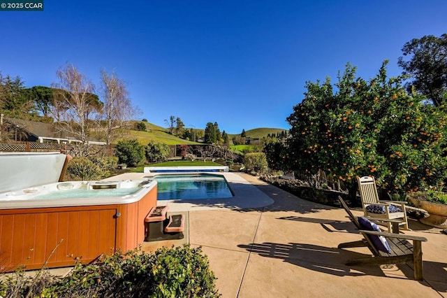 view of pool featuring a mountain view, a patio area, and a hot tub